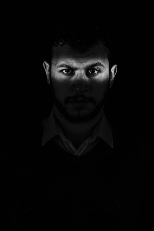 a man in black shirt looking at camera with dark background