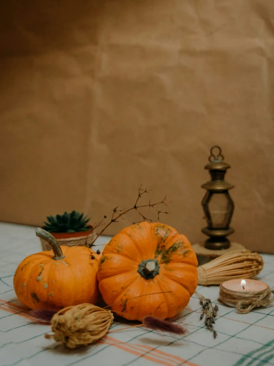 some orange pumpkins sitting on a table near two candles