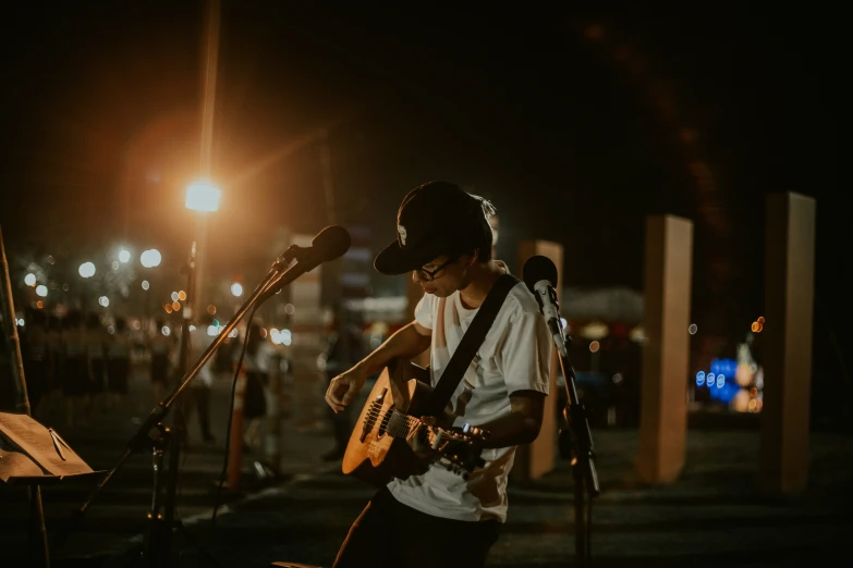 man playing guitar while singing into microphone on stage