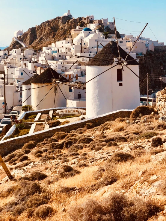 a few white buildings and white windmills on a hill