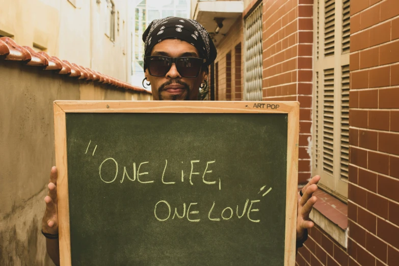 a man is holding up a chalk board that says one life