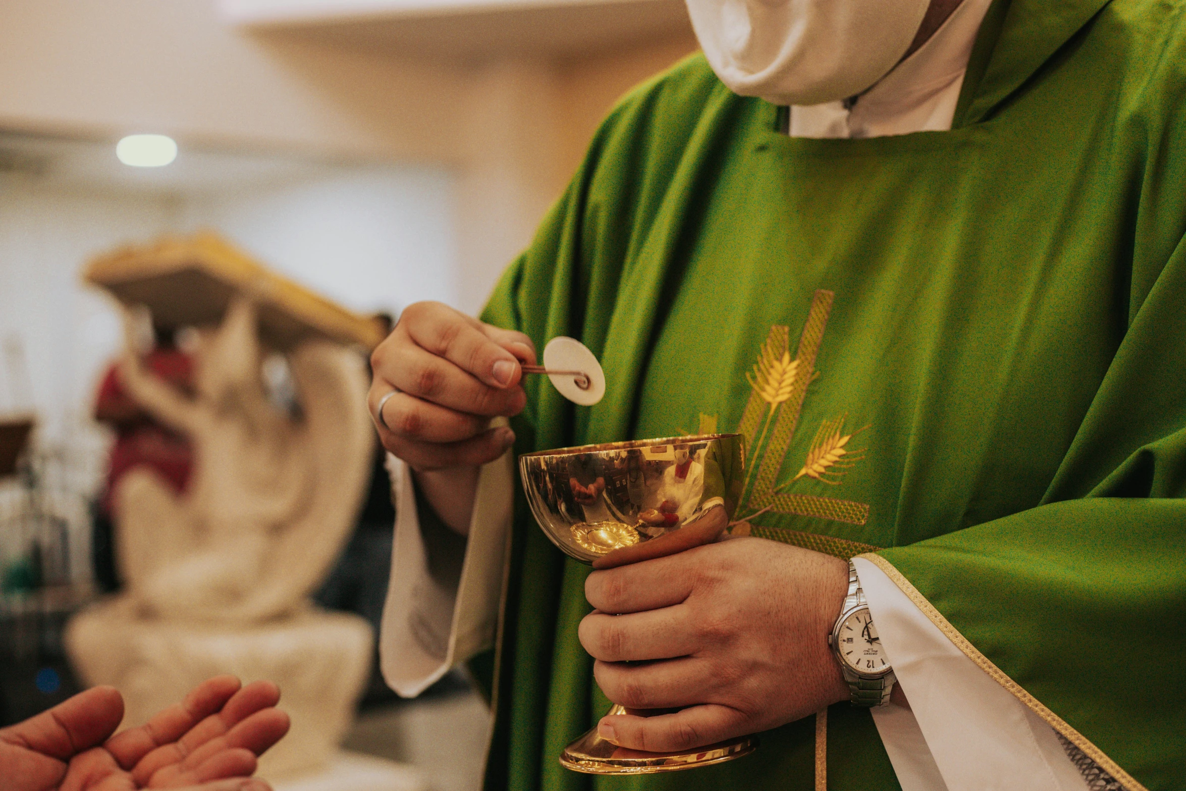 a priest holds a chalice at his side during a mass