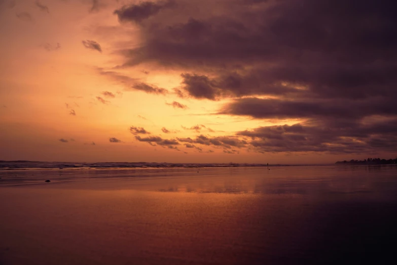 a person riding on top of a beach under cloudy skies