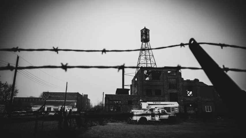 a tall tower stands behind barbed wire in front of a building