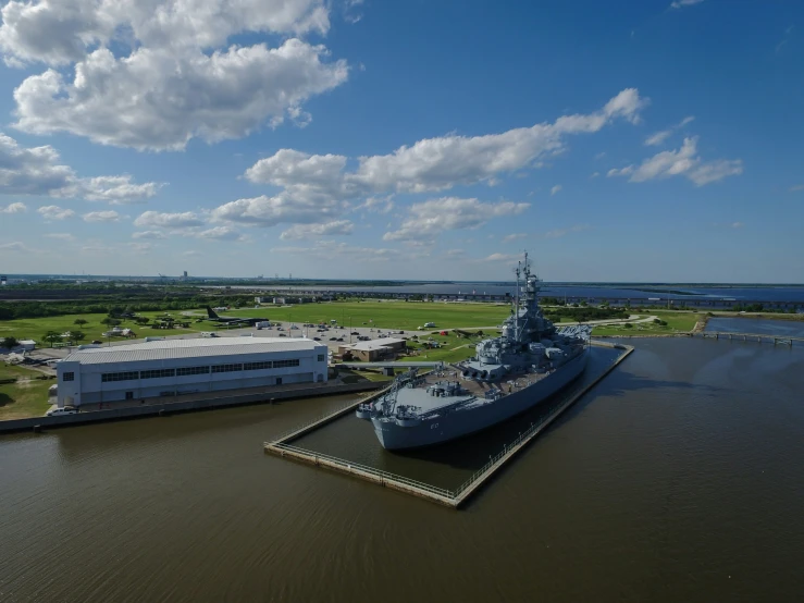 a large military ship in a body of water near a harbor