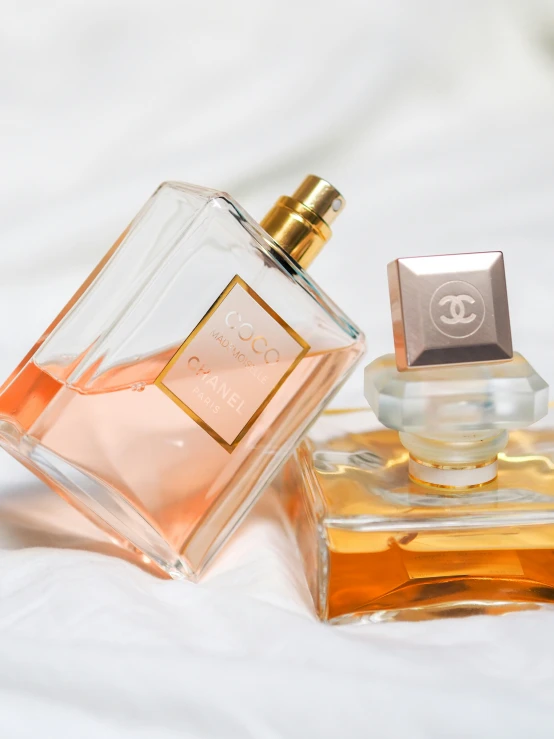 chanel perfumes sitting next to each other on a bed