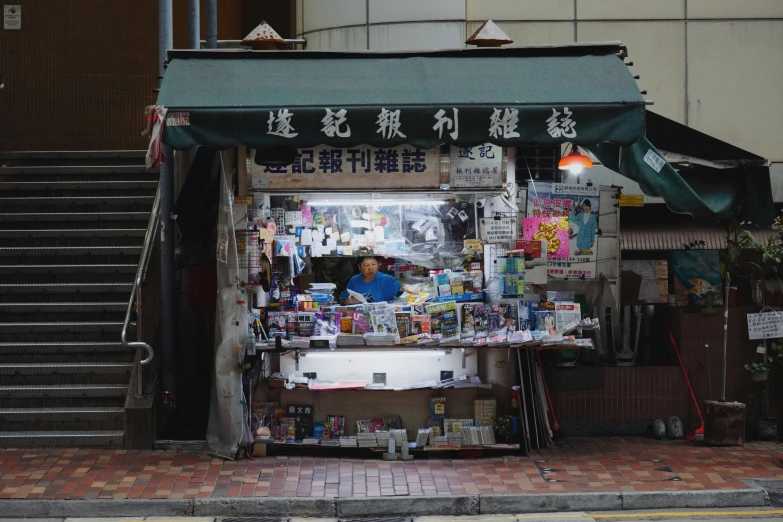 an old book shop on a brick street with people seated in front