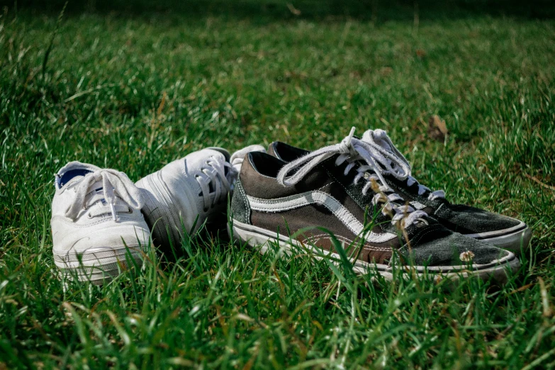 two old shoes sitting in the grass one broken and another dirty