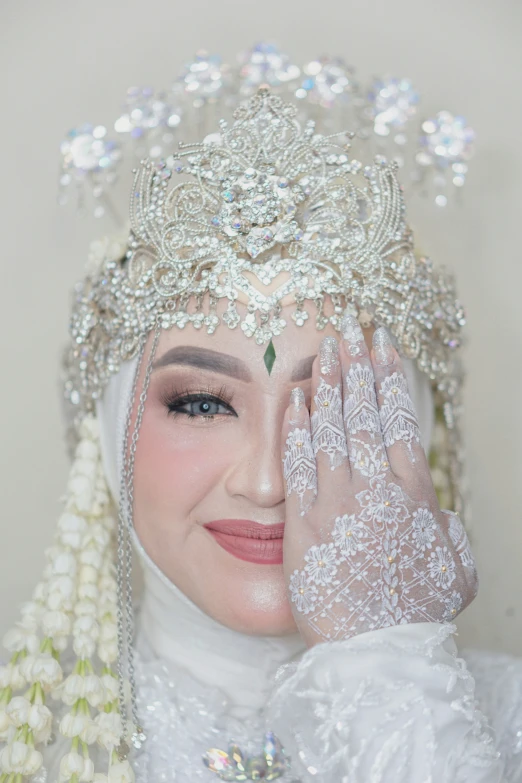 a woman wearing a bridal crown with a diamond tiara and pearl veil on her head