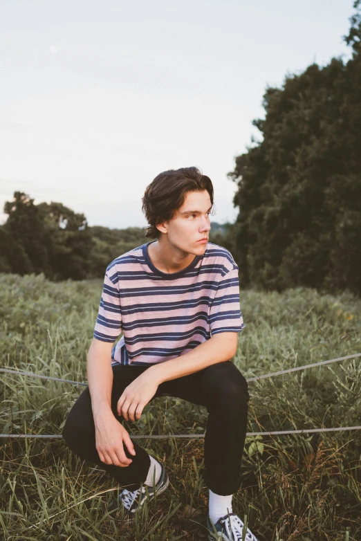 a man sitting on a wire fence in a grassy field