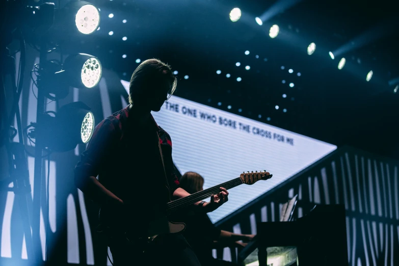 someone is playing guitar on stage at a concert