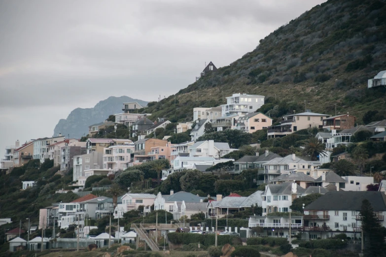 houses along a hilly hill, with green trees on the slope