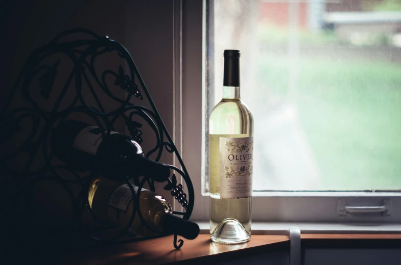 wine bottle on window ledge next to a metal rack with wine