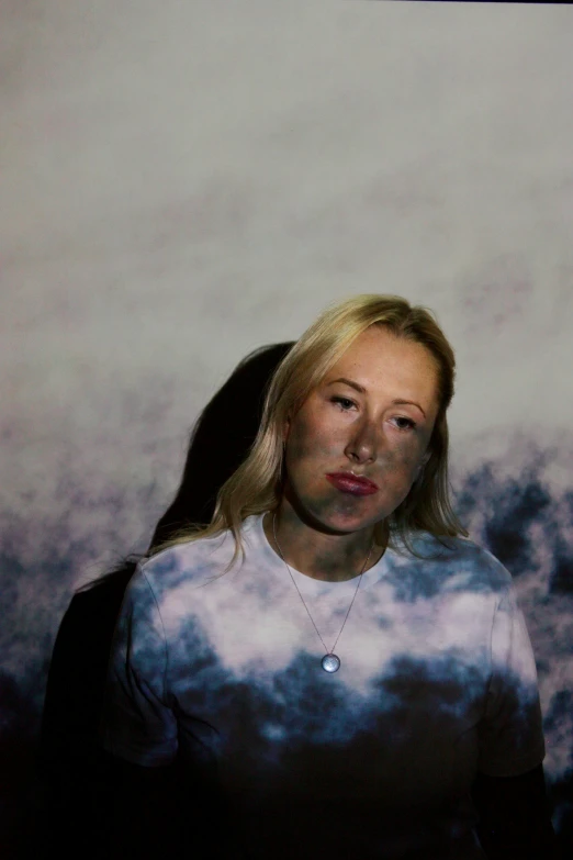 a woman standing in front of a painting of clouds