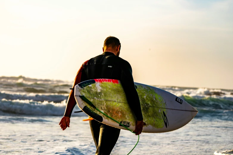 a man walking into the water with a surfboard