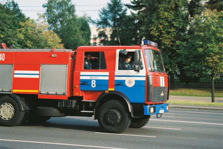 a fire truck driving on a street with trees behind it