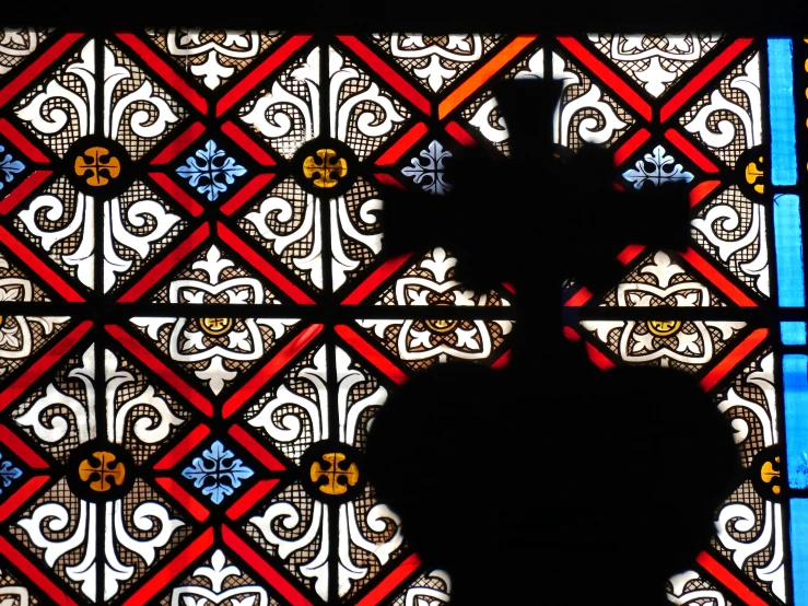 the silhouette of a person standing in front of an ornate glass window