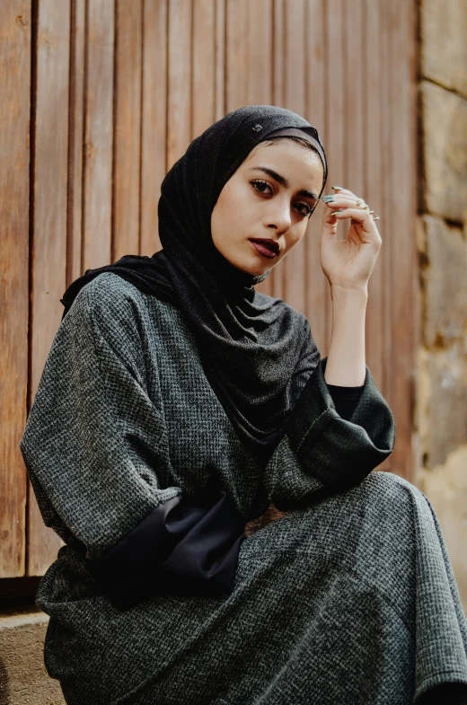 a woman wearing a head scarf sits on stairs