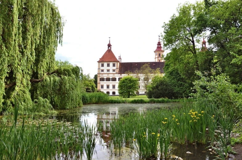 a big house sitting above some water and green vegetation