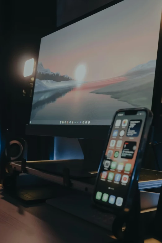 a cellphone sitting on a stand next to a computer monitor