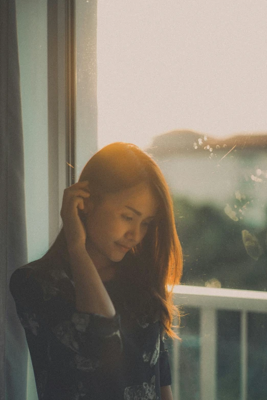 a woman is holding her phone and looking out of a window