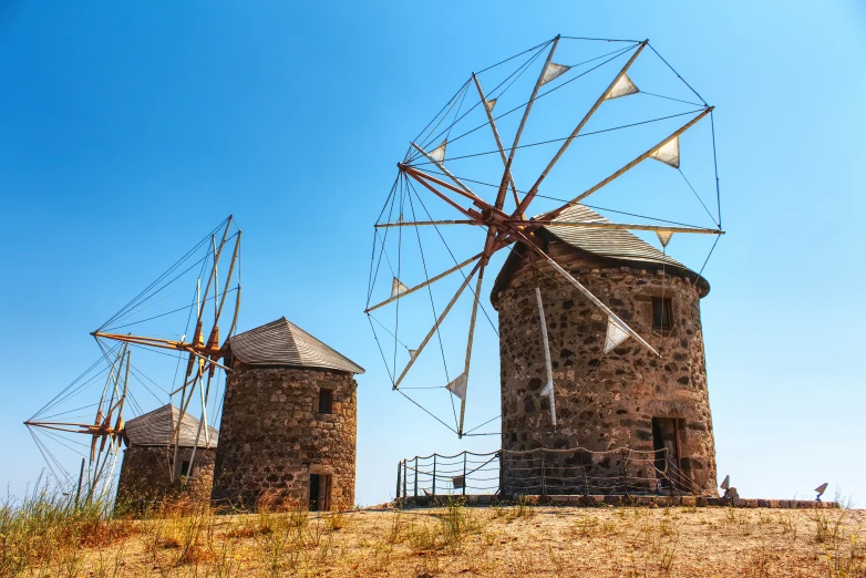 three windmills with flags next to a fence