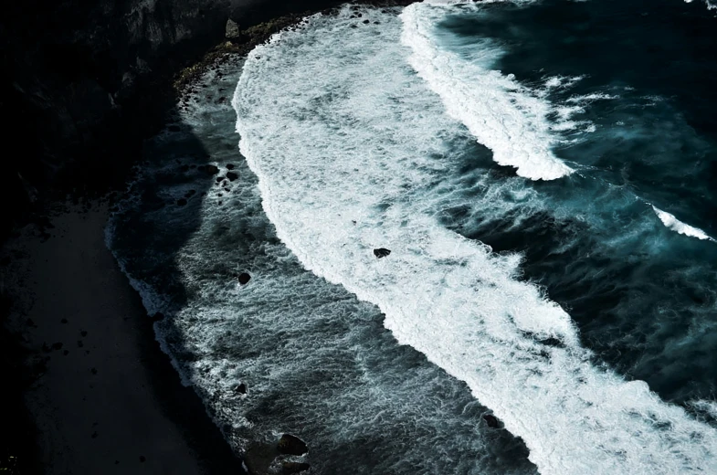 an aerial view of waves hitting onto a beach
