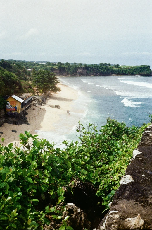 an ocean cliff overlooks an overhanging sandy beach