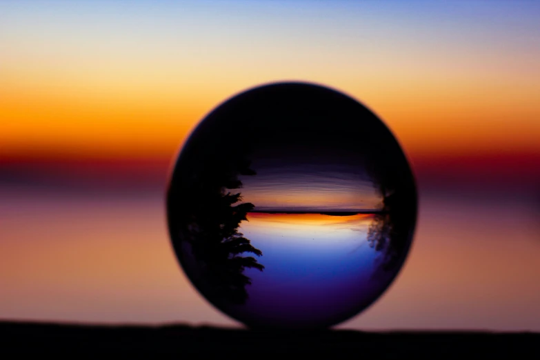 a mirror reflects the sunset behind a tree