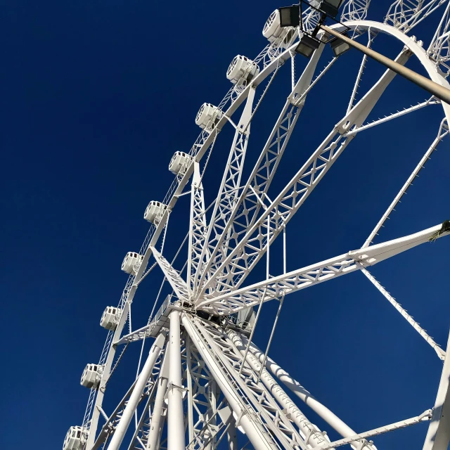 a ferris wheel is standing against a blue sky