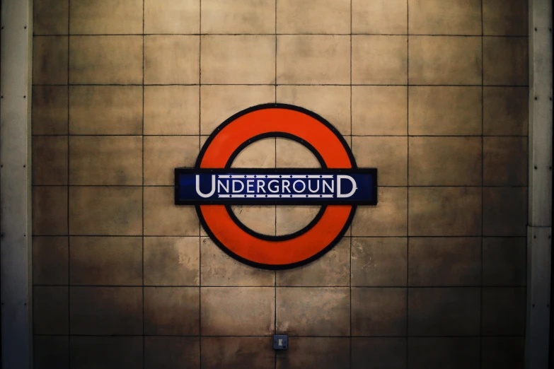an underground sign hanging on a tiled wall