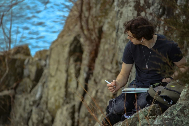 a person sitting on top of a cliff next to the ocean