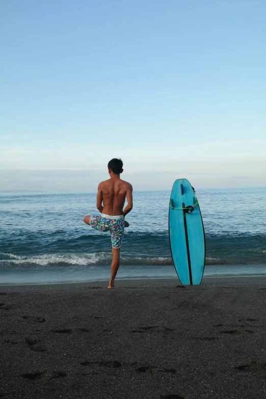 a person standing next to a surfboard on the beach