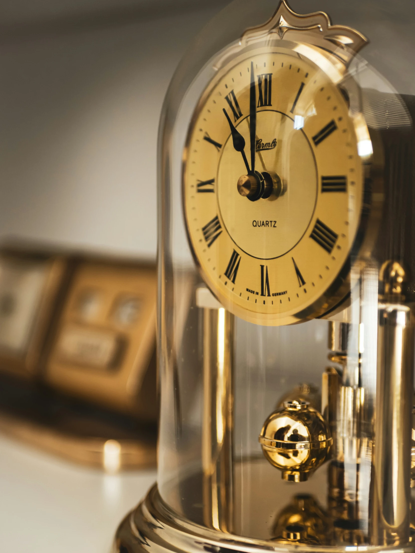 a golden clock with roman numerals under glass