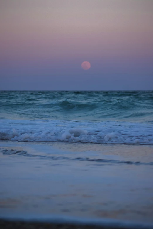 the sun setting at the beach in the ocean