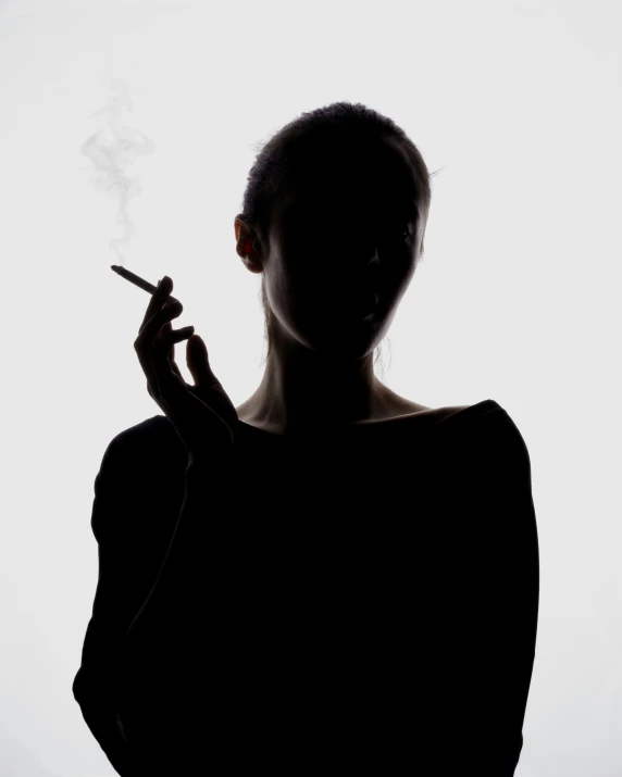 a girl smoking a cigarette standing in a light room