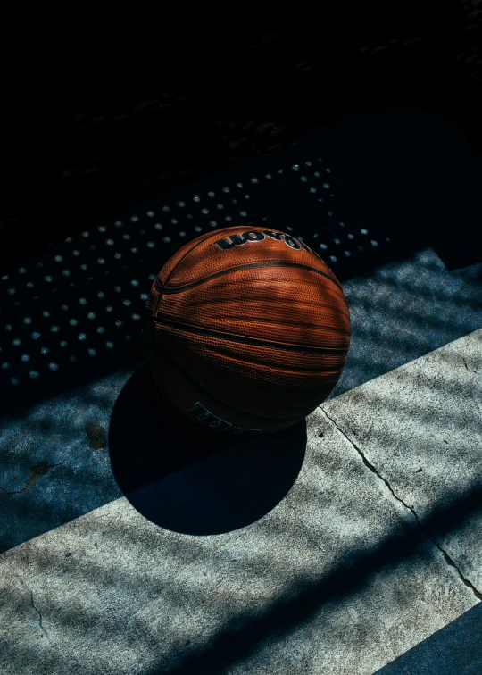 a basketball sitting on the sidewalk in the dark