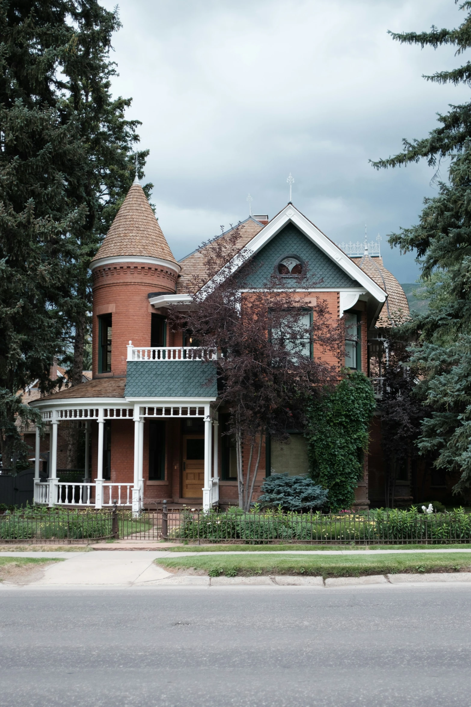 large home surrounded by trees and hedges near the sidewalk