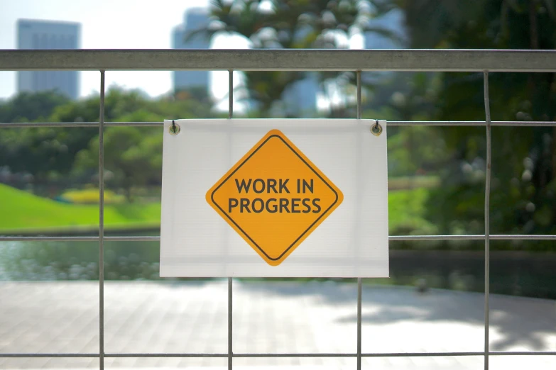 a work in progress sign posted on a fence