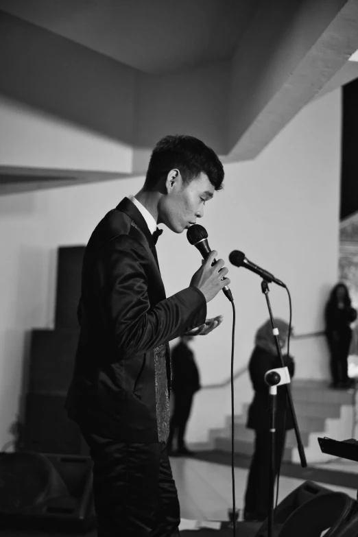 a man with glasses on, standing in front of a microphone