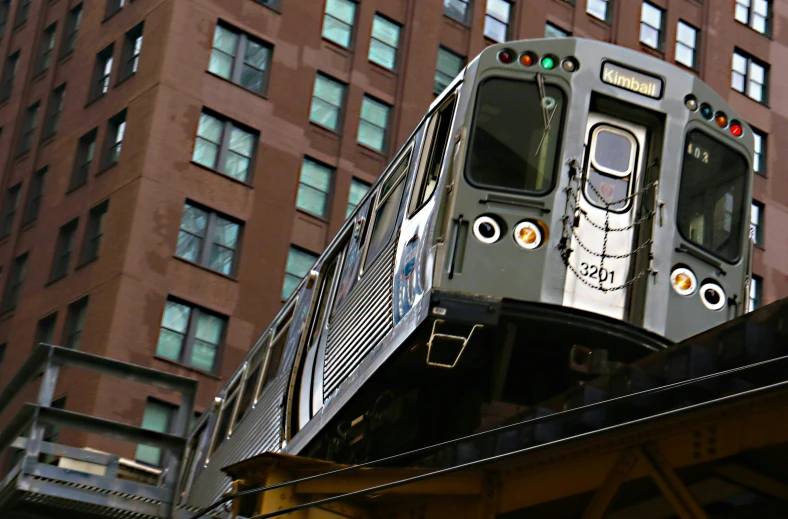 a train with eyes painted on the side rides near buildings