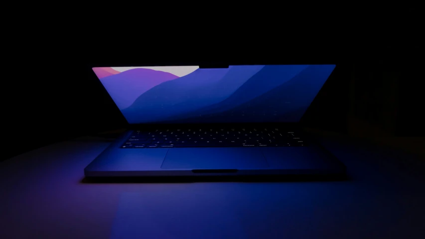 a lap top computer on a desk illuminated by a purple light