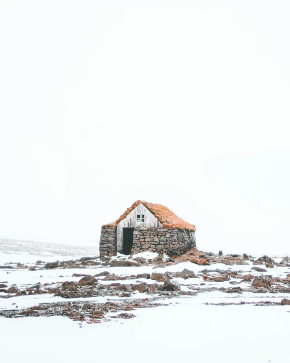 old shack in a snow - covered field on a clear day