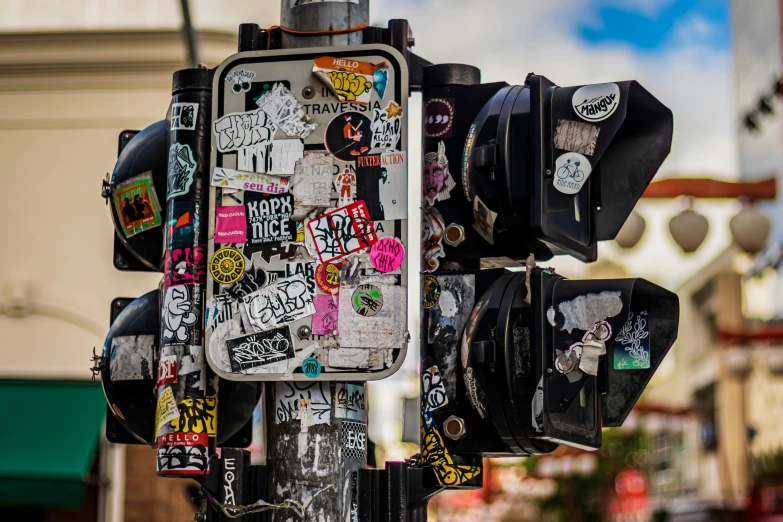 this pole has several street signs that are covered in graffiti