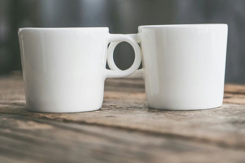 two white coffee mugs placed on a wooden table