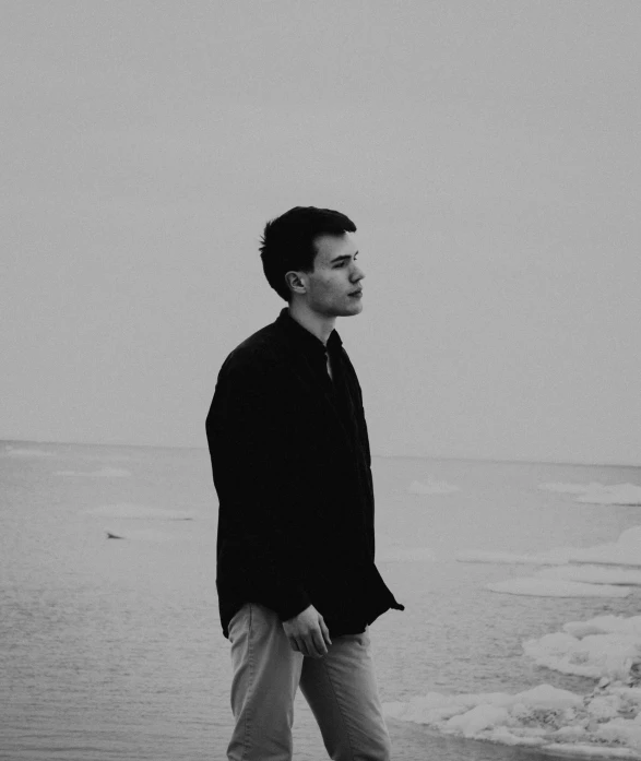 a man is standing on a beach in black and white