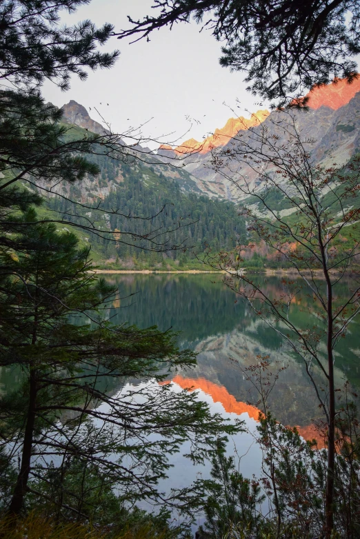 a lake surrounded by some trees and mountains