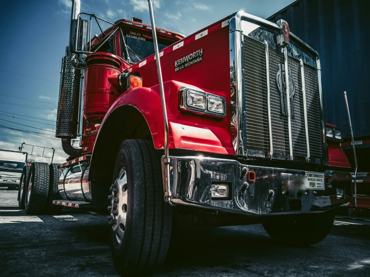 red semi truck with trailer cab, parked at a shipping port