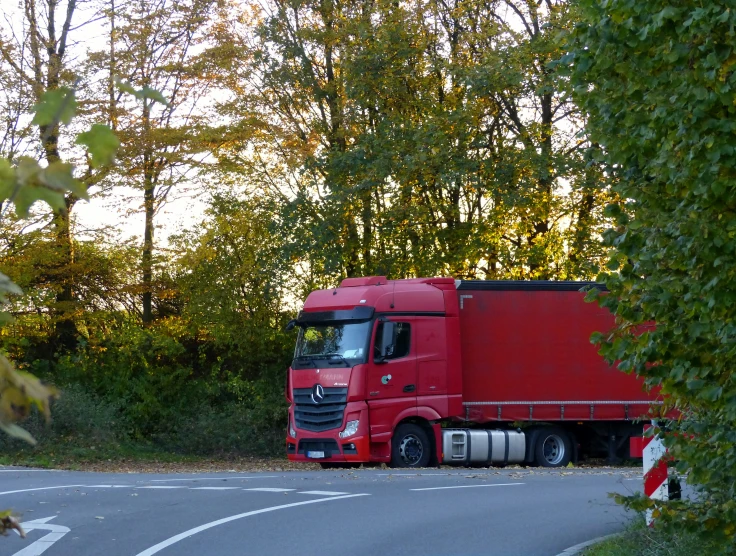 a truck traveling along the highway between some trees