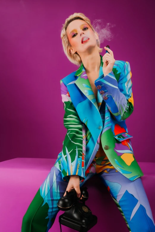 a woman in colorful suit smoking a cigarette while sitting